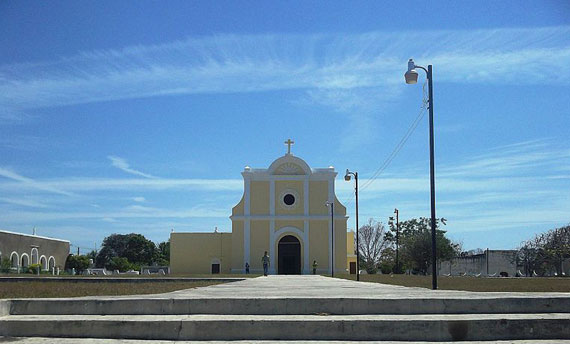 The blue sky towers above the yellow church located in the town center of Yobain, Yucatan