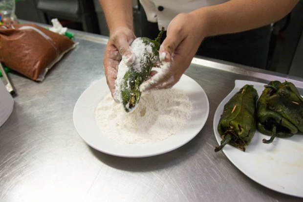 Poblano peppers being covered in flour before being fried