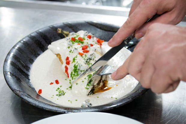 A fork and knife cutting into a chile en nogada