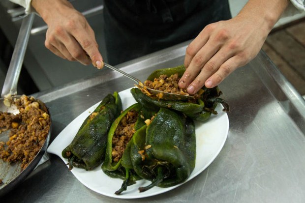 Poblano peppers being filled with a minced meat and fruit mixture