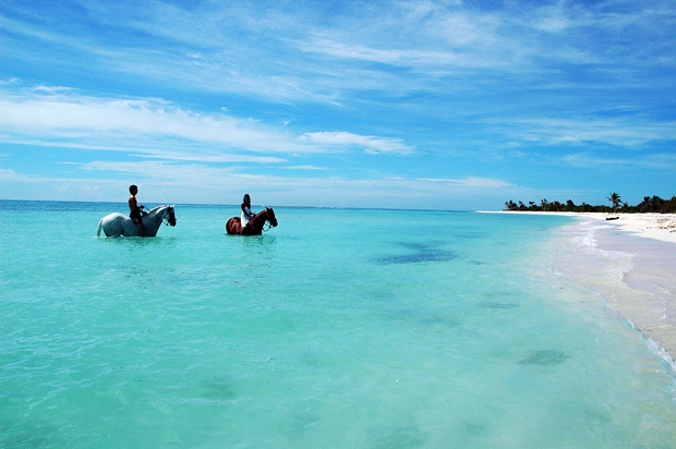 A couple horseback riding in the middle of the Caribbean Sea off the coast of the Riviera Maya