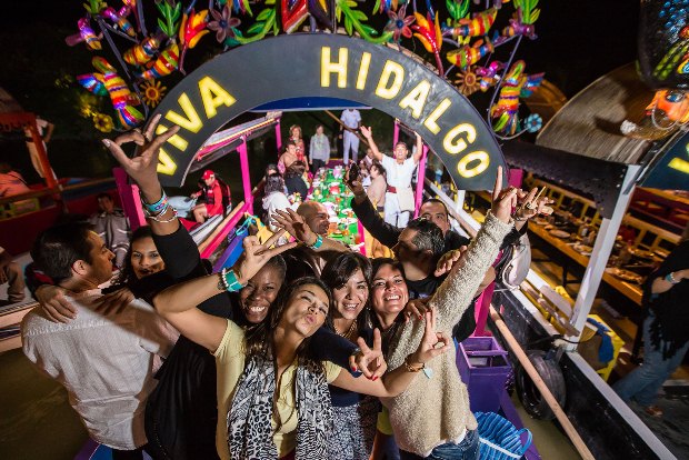 A groups of guests celebrate aboard a wooden gondola-style boat at Xoximilco in Mexico's Riviera Maya