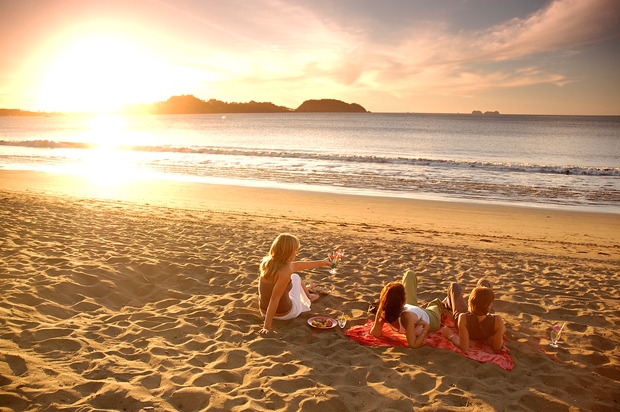 Three women at a beach in Guanacaste, Costa Rica, enjoying a beautiful sunset