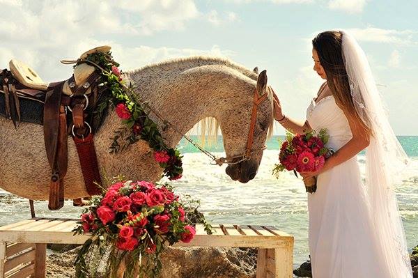 A bride carressing a horse at the beach in the Riviera Maya, Mexico