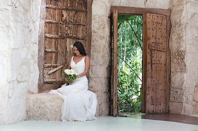 A bride looks down at her flowers outside of a hacienda in the Riviera Maya, Mexico