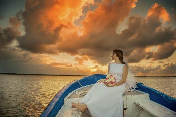 A model sits on a boat in the Nichupte Lagoon at sunset as part of the Riviera Maya Destination Wedding Photo Shoot