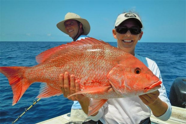 A woman holds up her catch of the day from a fishing trip off the coast of Cancun, Mexico