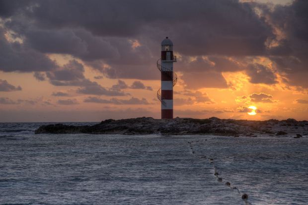 Caribbean sunset against the backdrop of a lighthouse