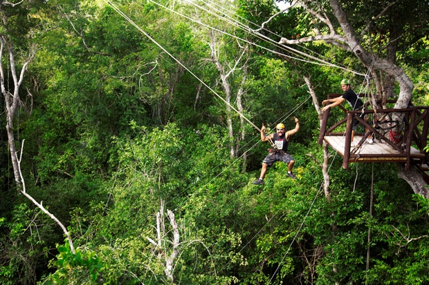 A guest flies through the jungle canopy on a zip line at Selvatica, located in Mexico's Riviera Maya