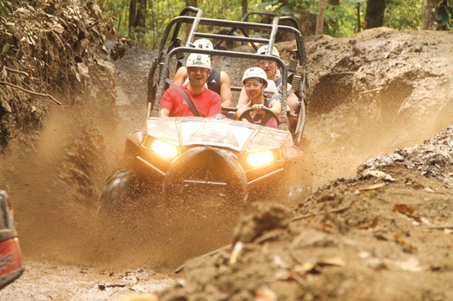 A group of tourists race through the mud in the mountainside jungle of Puerto Vallarta on Amstar dmc's Extreme Adventure tour.