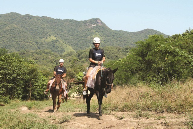 A couple goes horseback riding through the Sierra Madre mountains on the Amstar dmc Outdoor Adventure tour.