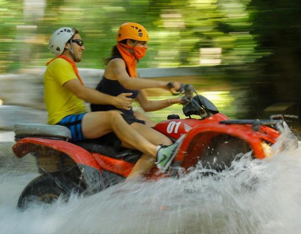 A couple races through the Sierra Madre Mountains aboard an ATV on the Amstar dmc ATV tour.