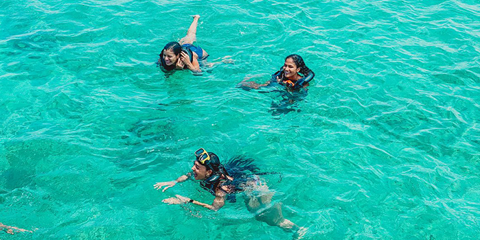 3 people swiming in the ocean near Aruba