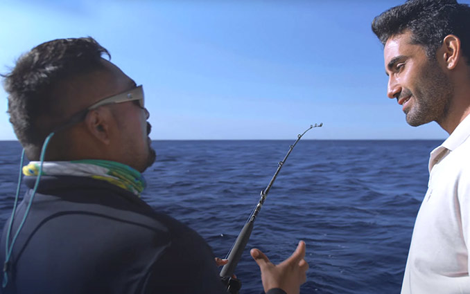 Fishing charter guide helping a tourist to learn hoy to fish