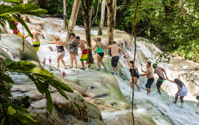 People holding hands while climbing Dunn Rivers Falls at a teambuilding event