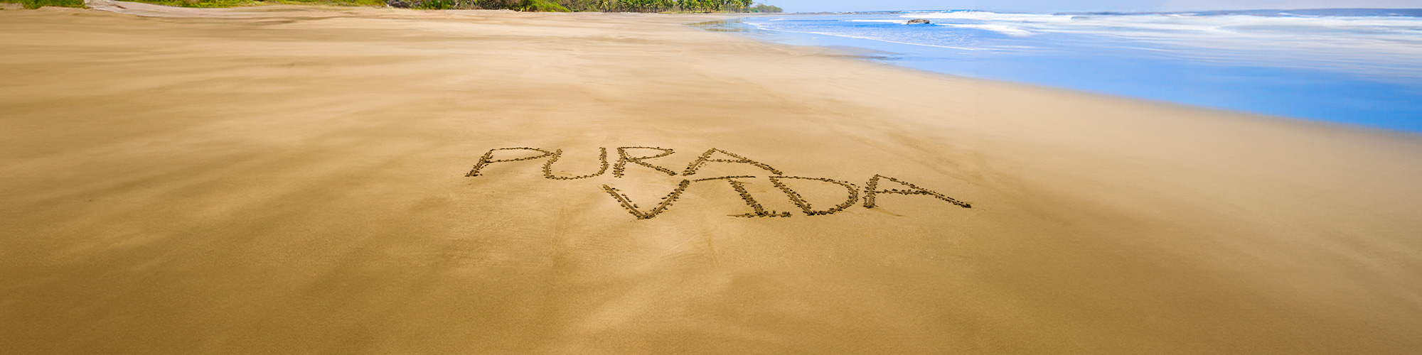 Pura vida escrito en arena en playa de Guanacaste, Costa Rica