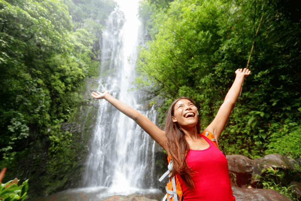 A smiling woman enjoying a waterfall in Hawaii.