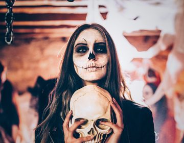 Woman painted for Halloween, while carrying a skull in her hands